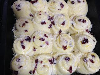 13、酥粒蔓越莓奶酪卷,然后放到温暖湿润处进行二次发酵至约2倍大，在表面刷一层蛋液，然后依次撒上适量香酥粒和蔓越莓碎