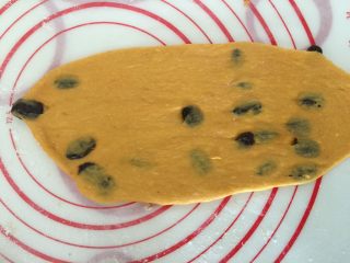 13、奶香南瓜葡萄干小吐司,面垫上撒些粉，取一块面团擀成牛舌型卷起来