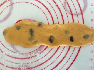 14、奶香南瓜葡萄干小吐司,收口朝下，再擀成长牛舌型，宽度和吐司模具差不多，卷起来，2.5圈