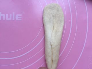 15、黄油面包卷,拿一个放平，收口朝上。用擀面杖从中间先往上擀开。