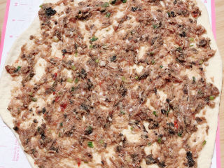 13、梅干菜烧饼,将肉馅儿均匀平铺在面饼上。