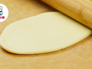 5、零难度脆底蜂蜜小面包,取出松弛好的面团，依次用手压扁，擀成牛舌状，从一头卷起，再对半切开