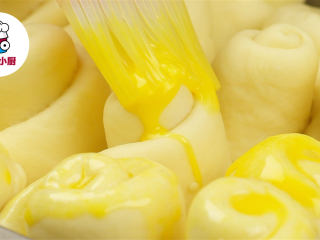 8、零难度脆底蜂蜜小面包,发酵好的面团表面刷上蛋液，撒上适量熟白芝麻，放入预热好180℃的烤箱中烤制20-25分钟至表面上色，底部酥脆