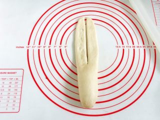 11、牛奶炼乳蔓越莓软欧,用刮刀在擀开的面片中间纵切一刀。
