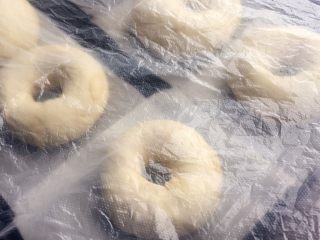 12、杏仁片贝果,每个贝果低下垫上提起拆好的油纸,盖上保鲜膜发酵30-40分钟左右;
