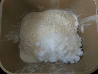 3、原味麦香小面包,用高筋粉覆盖住液体表面后，加糖和盐。