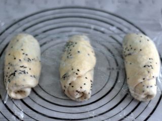 9、黑芝麻吐司,将面团擀开卷成圆筒状，3个都做同样处理，盖上保鲜膜静置15分钟左右。