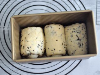 10、黑芝麻吐司,再次擀开成长条状，面团卷起，收口朝下放置，将面团放入吐司模。