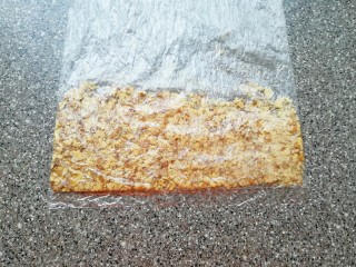 2、麦片芝麻核桃酥,核桃仁装进保鲜袋里面，用擀面杖压碎。