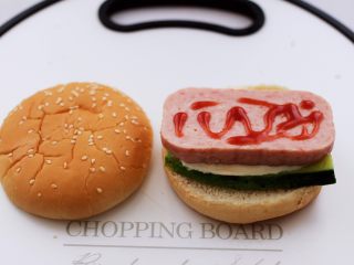 8、午餐肉黄瓜汉堡包,在午餐肉上面挤上番茄酱。