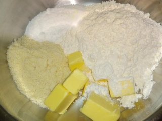 3、兰姆葡萄夹心饼乾,拿调理碗将无盐奶油~面粉~糖粉~杏仁粉一起入，用手将食材搓揉均匀至散沙状~