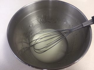 2、可可旋风瑞士卷（后蛋法）,水和油倒进打蛋盆里进行乳化，手动打蛋器搅拌均匀呈乳白状，多搅拌一会，让水和油充分融合在一起。