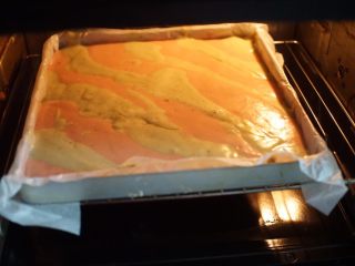 11、圣诞蛋糕卷,烤盘铺上油纸，将两种面糊分别间隔倒入烤盘中，放入预热好的烤箱中层以上下火150摄氏度烤20分钟