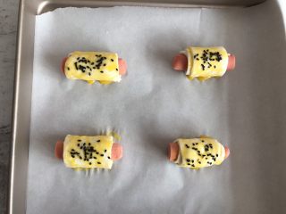 7、手抓饼版香肠可颂,撒上一点黑芝麻，放入提前预热好的烤箱上下火200度烤15分钟即可