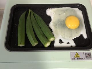 5、蔬菜三明治,烤盘倒少许油，打入鸡蛋，放入秋葵