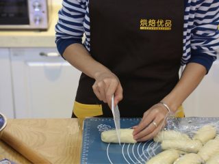 9、蜂蜜椰蓉小面包,9.将卷好的面团，对半切开，得到两个面团。
