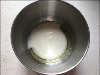 2、糯米蛋糕,100克牛奶和15克玉米油放入盆中,用手抽搅拌均匀并充分乳化。