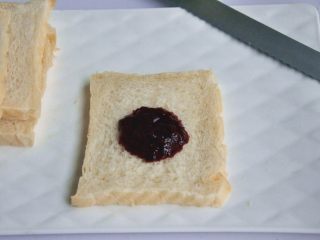 11、口袋三明治,出炉后立即脱模,在晾架上散热,取出后最好先侧放一会儿,以免凹腰,待完全凉透再切片,取一片吐司,抹上草莓桑葚酱。