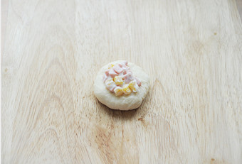 5、时下超级火爆的萌哒哒面包【面包超人挤挤面包】,发酵好的面团取出排气，分成16等份，取一份滚圆摁扁，中间放入馅料并包起来，收口处掐紧；