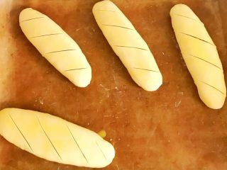 11、千层酥皮香肠卷,重复做好两外2个，表面刷鸡蛋液，用锋利刀片切割几下，便于烤制过程中散发热气