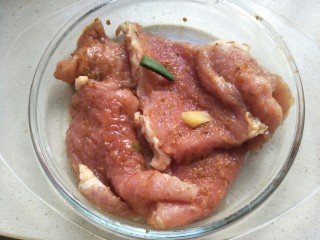 11、炸猪排,加入葱段和姜片，用手抓匀腌制20分钟左右。