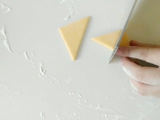 3、大风车彩色小馒头,黄面团，揉捏排气后，切出一个正方形，然后，沿着对角线，切开，平均切出四个三角形。
