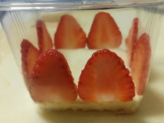 16、送你一朵小红花,边角的地方略微有几毫米的空隙不用管，往里面舀入奶油，再撒上草莓丁，喜欢果酱的可以再加一层果酱。再铺一层蛋糕片，奶油，草莓丁，一直铺到盒子顶