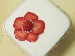 17、送你一朵小红花,最上面一定要用淡奶油铺，用刮刀把表面抹平。最后再放上圆形的草莓片。中间用奶油挤出小球做装饰。这道甜品就完成了。