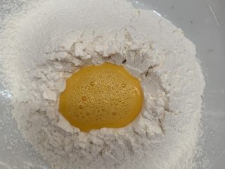 5、腊肠牛角包,鸡蛋搅均倒入面粉里，留一点刷表面。