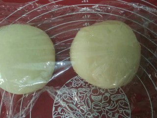 6、奶油奶酪面包,取出，排气，分成两个，揉圆盖保鲜膜松弛15分钟