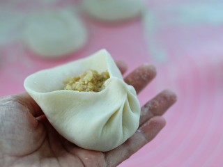 18、东北猪肉酸菜馅包子,左手托住底部，用右手的拇指和食指沿着边缘一圈捏出褶状