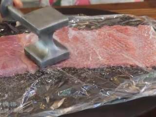 3、芝心猪排,铺上保鲜膜，用肉锤敲打猪肉