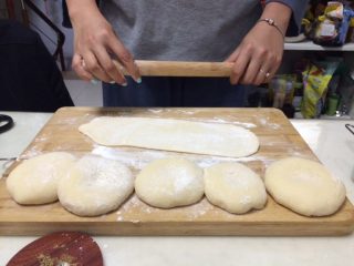 4、椰蓉吐司,二次揉面结束后，取出面团，面包机不关，面板上撒少许干面粉，将面团分成6份，揉成团，放置10分钟让面团醒一下