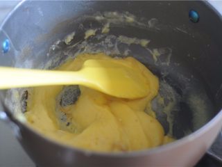 6、#不一样的泡芙#卡仕达焦糖泡芙塔,沸腾后变得更加粘稠,搅拌的时候可以看到锅底程度,立刻换成硅胶刮刀。厚重的卡仕达糊变成粘稠柔软,有光泽即可,充分进行加热,将牛奶中的水分蒸发掉