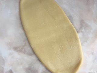12、一发也能做出超级柔软的土司,15分钟后，取一个面团，揉下，再擀成如图的牛舌状，卷起来；