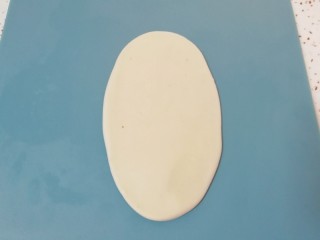 5、枣泥核桃卷,包好的油酥皮收口向上压扁，擀成椭圆形卷起。