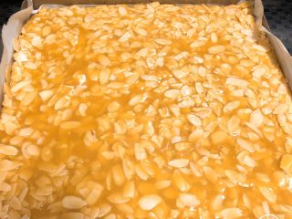 10、焦糖杏仁酥,铺好的焦糖杏仁酱如图所示，接下来进烤箱，上火180度，下火180度，烤20分钟左右，主要看颜色，不要烤糊，根据颜色判断具体烤的时间。