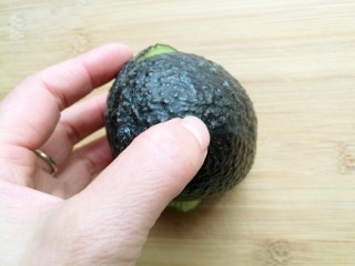 3、辅食计划十牛油果香蕉卷,双手握住牛油果上下反方向转动，我一个手要拍照，亲们看懂就行。