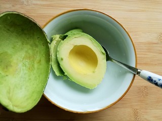 6、辅食计划十牛油果香蕉卷,用勺子把牛油果肉挖出来放在小碗里。