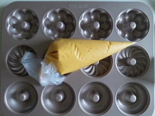 8、橙香甜甜圈（植物油版）,然后将面糊装入到裱花带内。我用的学厨不粘甜甜圈模具。不粘效果特别好,不需要抹油。