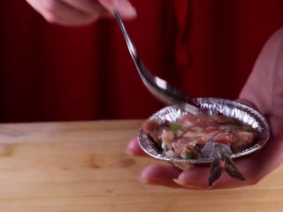 8、往虾里打入一颗蛋——虾扯蛋,然后借用勺子的底部，将肉馅压平。用勺子在肉馅上挖一个小的凹槽。