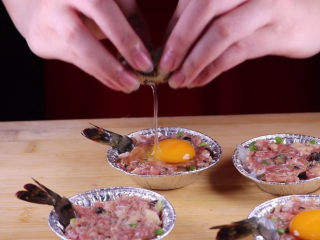 9、往虾里打入一颗蛋——虾扯蛋,取一颗鹌鹑蛋，将鹌鹑蛋打入肉馅表面上的凹槽中，这样蛋黄就比较容易定型。