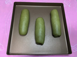 15、抹茶凤梨全麦面包,收口处压在下方，三个都整形好后移到烤盘中，使用烤箱发酵功能进行二次发酵，发酵同时烤箱中放一碗温水。