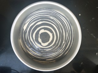 16、斑马纹戚风蛋糕,直到把所有面糊都舀完。然后端起来轻震几下,震平表面。同时震出大气泡