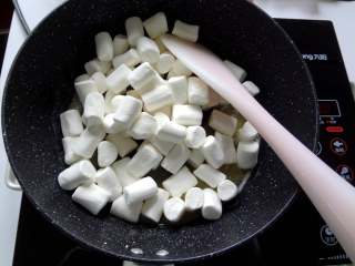 4、好吃到流眼泪的网红雪花酥,4.黄油全部融化后放入棉花糖，先用刮刀上下翻拌让棉花糖都裹上黄油