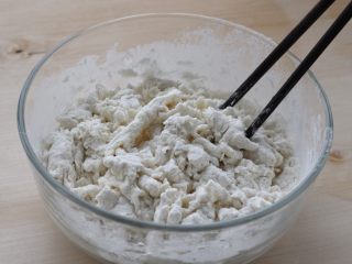 2、烫面豆沙饼,将面粉放入容器中,缓缓倒入热水,一边倒一边用筷子搅拌成棉絮状