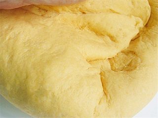 6、维尼豆沙馒头,然后把面团取出放在案板上用右手手掌根朝前推左手来回滚动，用巧劲把面团揉至光滑，手上无面为止