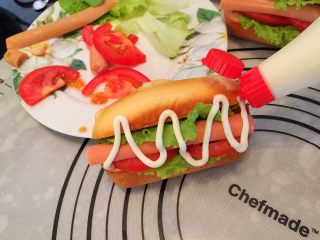 15、迷你热狗包,生菜洗净，蕃茄切片，热狗胚从侧面切入（别切断），放入生菜、蕃茄、火腿肠，挤上沙拉酱