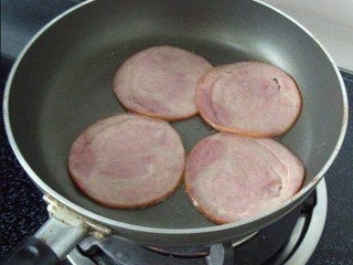 2、火腿肉松三明治,锅中滴少许橄榄油，把火腿入锅煎至两分钟；