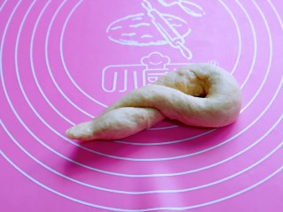8、松软老式小面包,将两头相接，左手固定顶部的中间，扭两圈，将相接的处塞进圆圈里，收口捏紧。